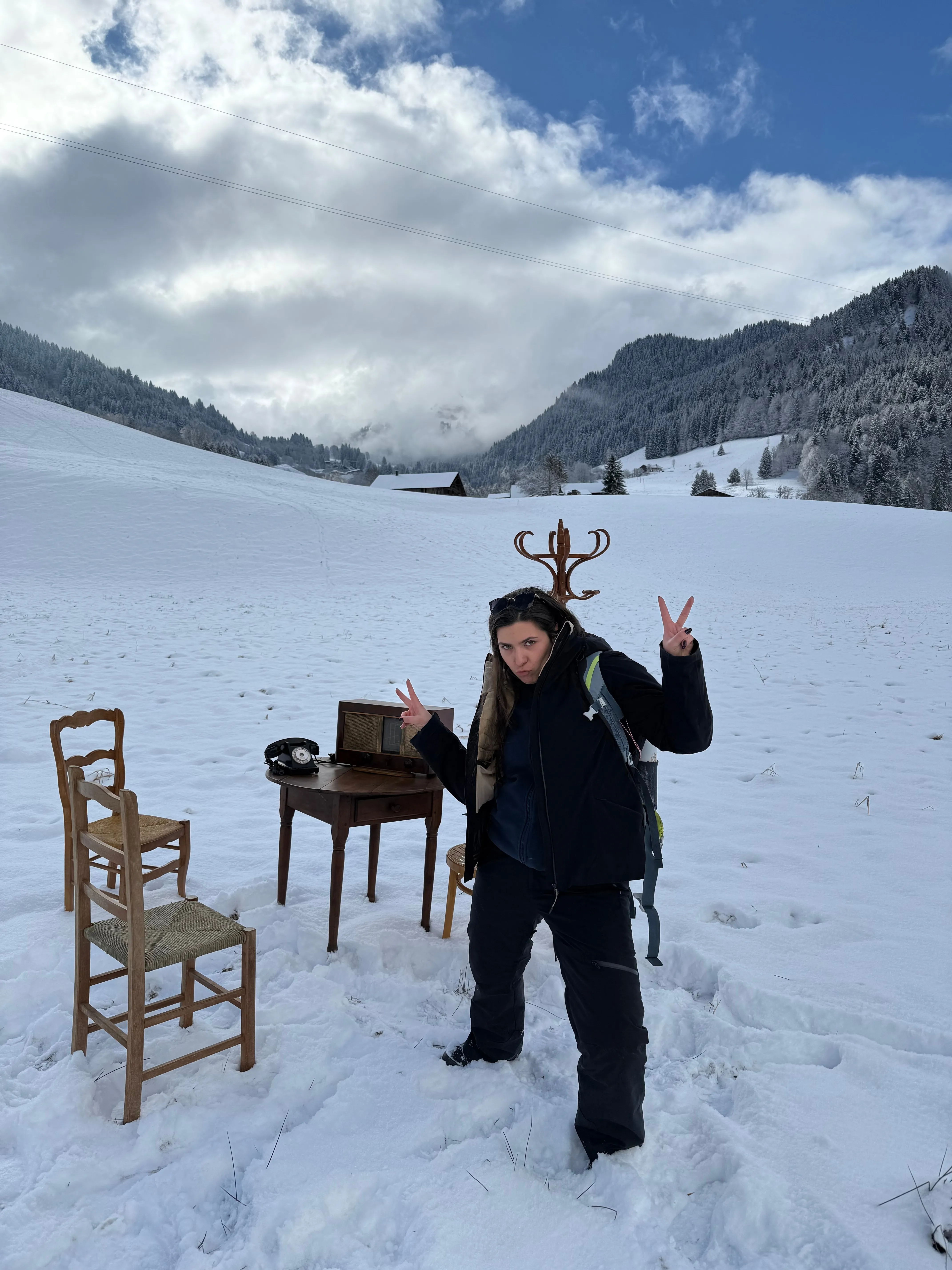 Un décor de bureau ancien avec chaises et téléphone installé en pleine neige, face aux montagnes de Megève.