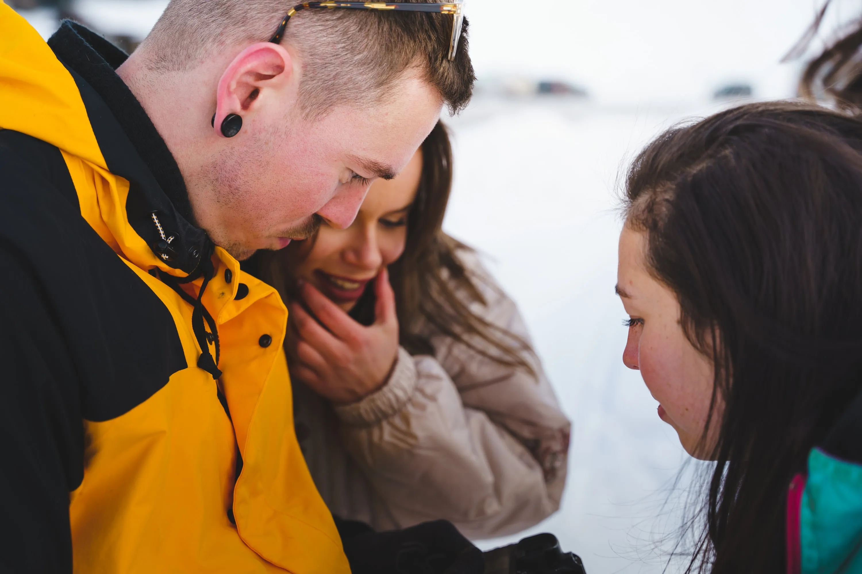 Deux modèles, dont un en veste jaune, partagent un moment complice dans la neige.