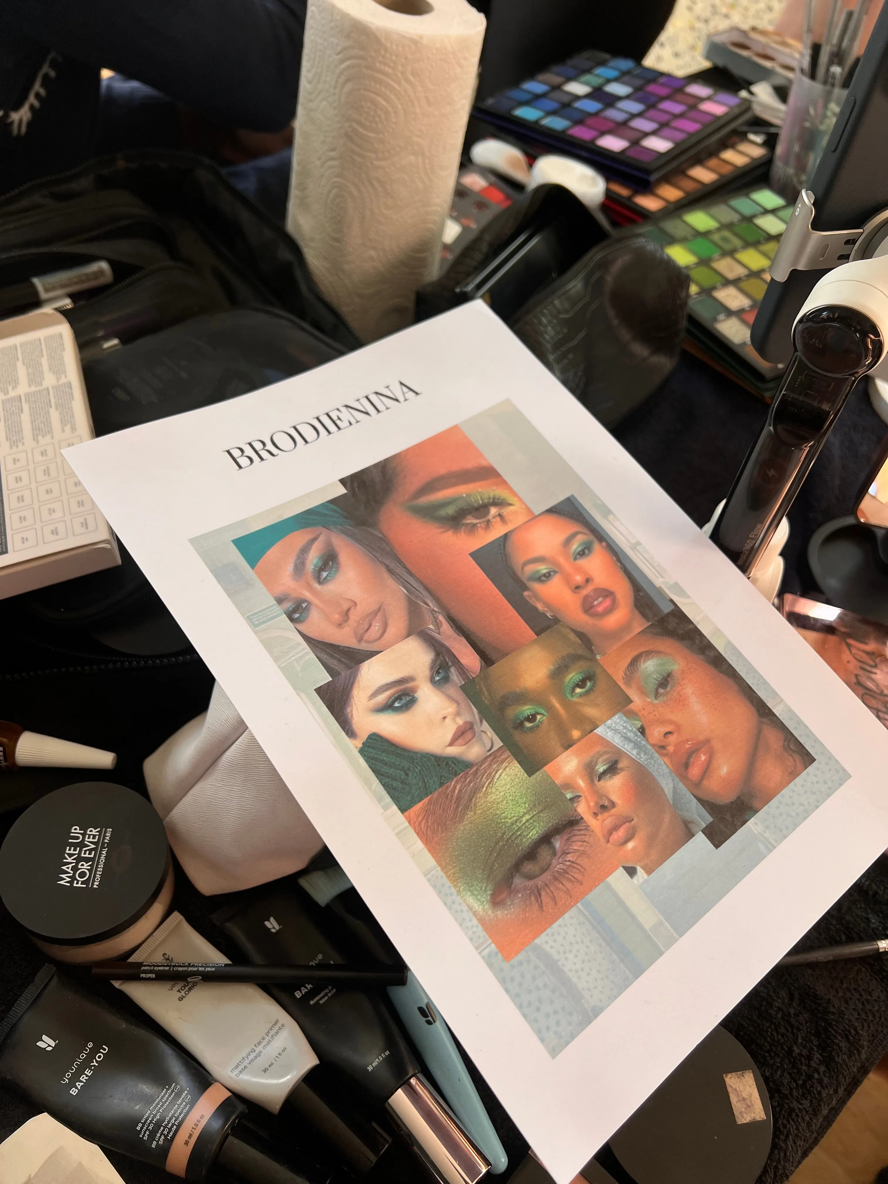 La planche d'inspiration maquillage posée au milieu des palettes et pinceaux des make-up artists.
