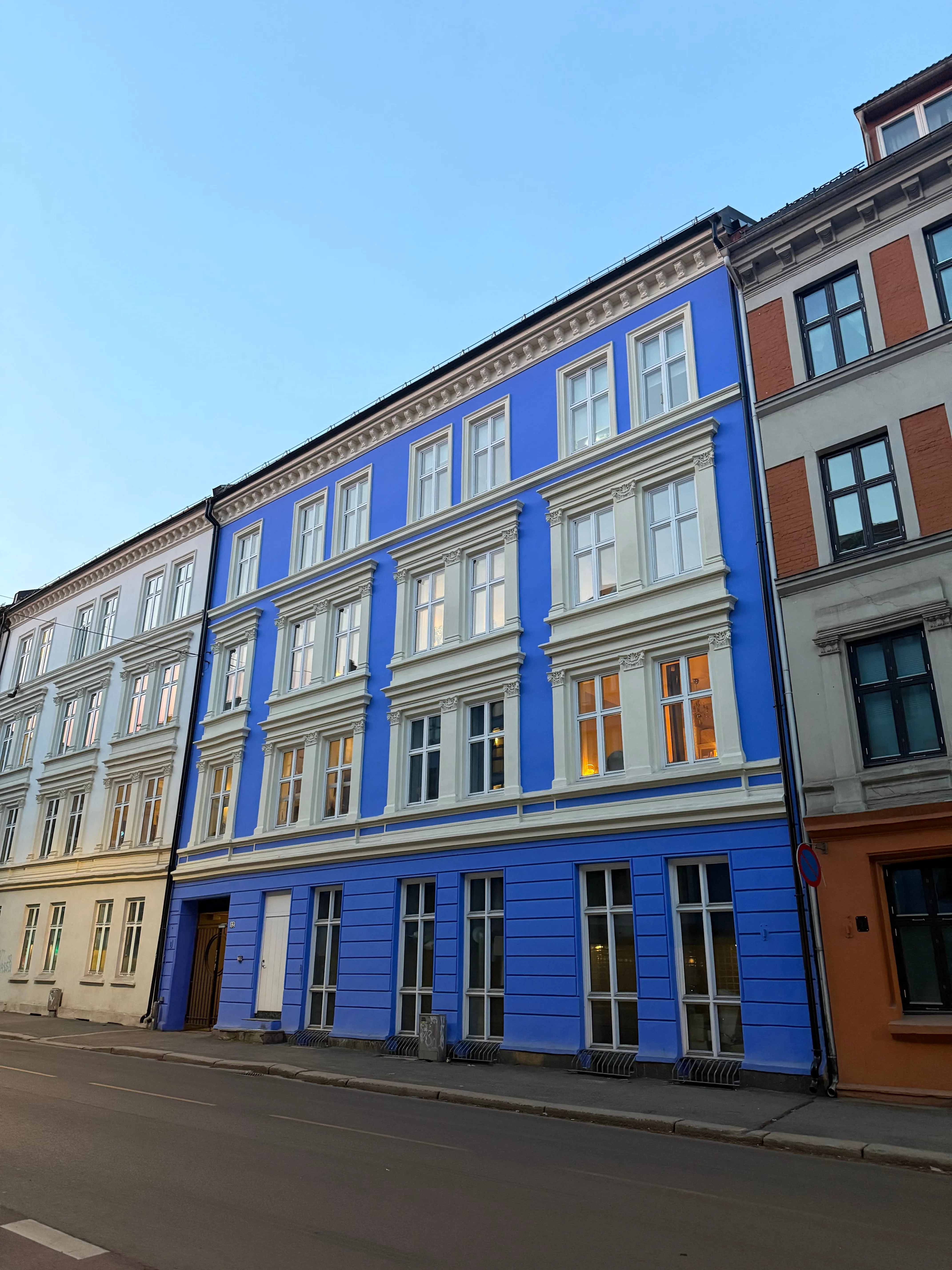 Un immeuble ancien à la façade bleu vif et aux fenêtres blanches, dans une rue d'Oslo.