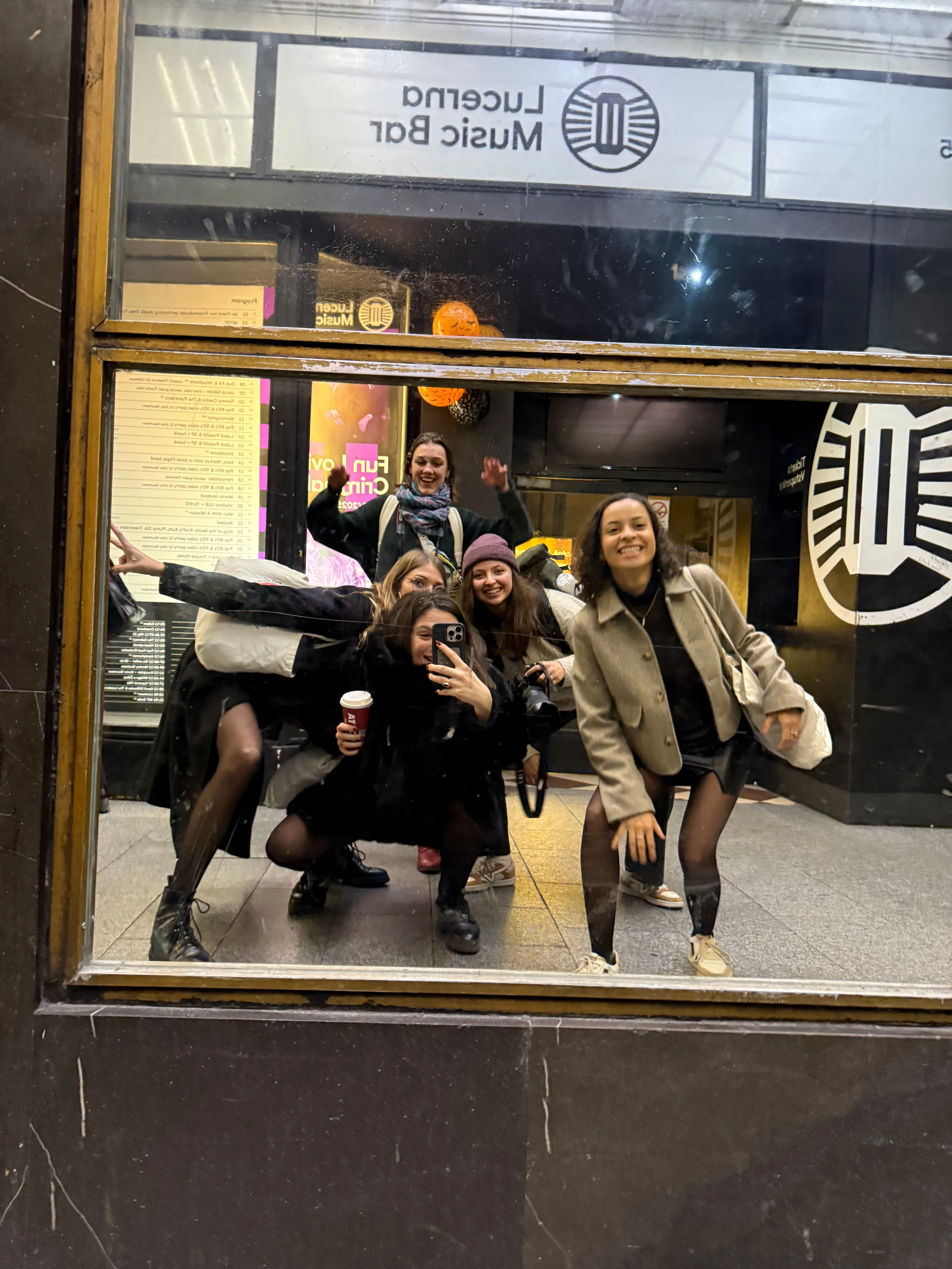 Selfie de groupe joyeux dans le miroir de la vitrine du Lucerna Music Bar à Prague.