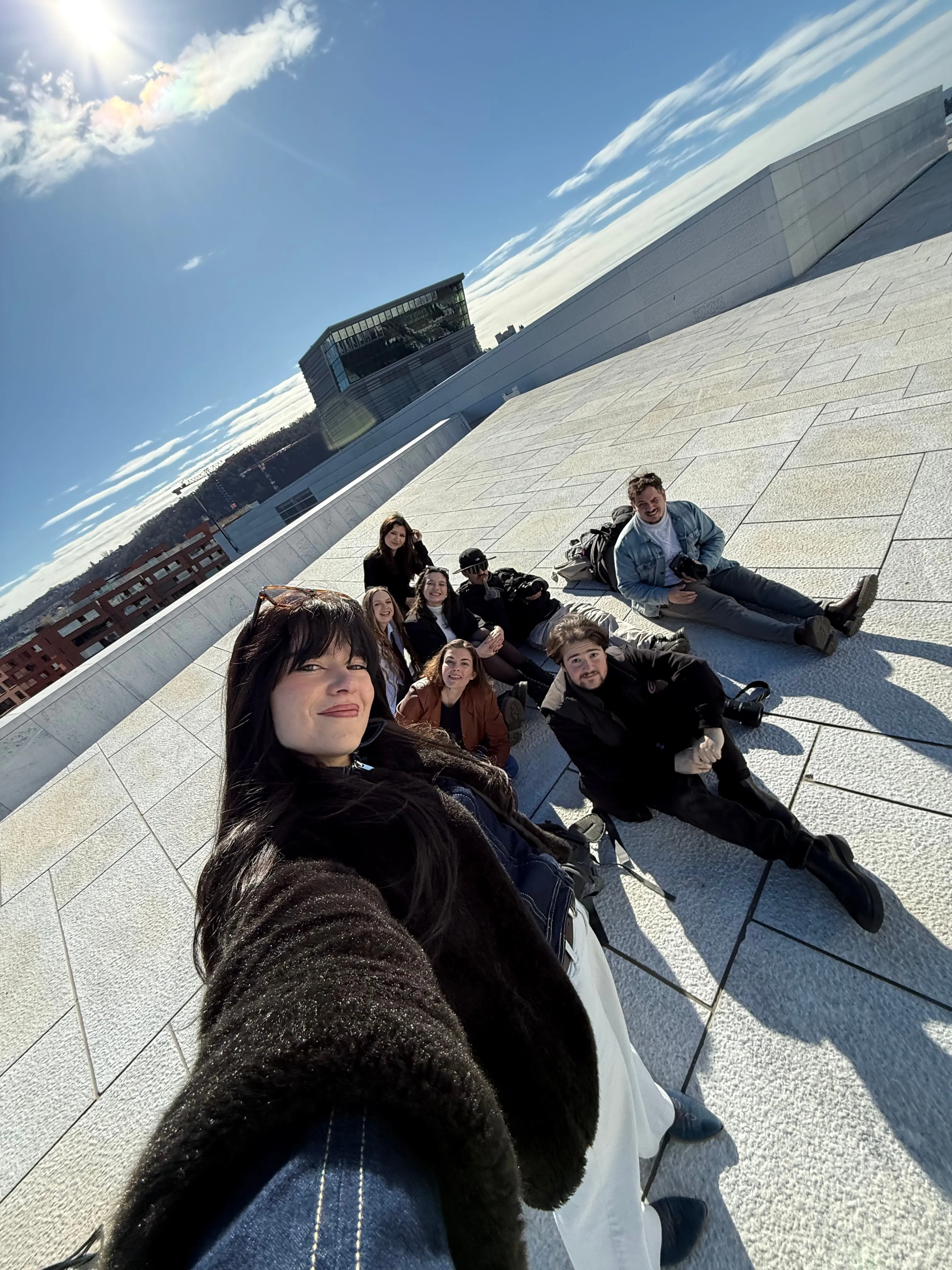 Selfie du groupe assis au soleil sur le toit en marbre blanc de l'Opéra d'Oslo.