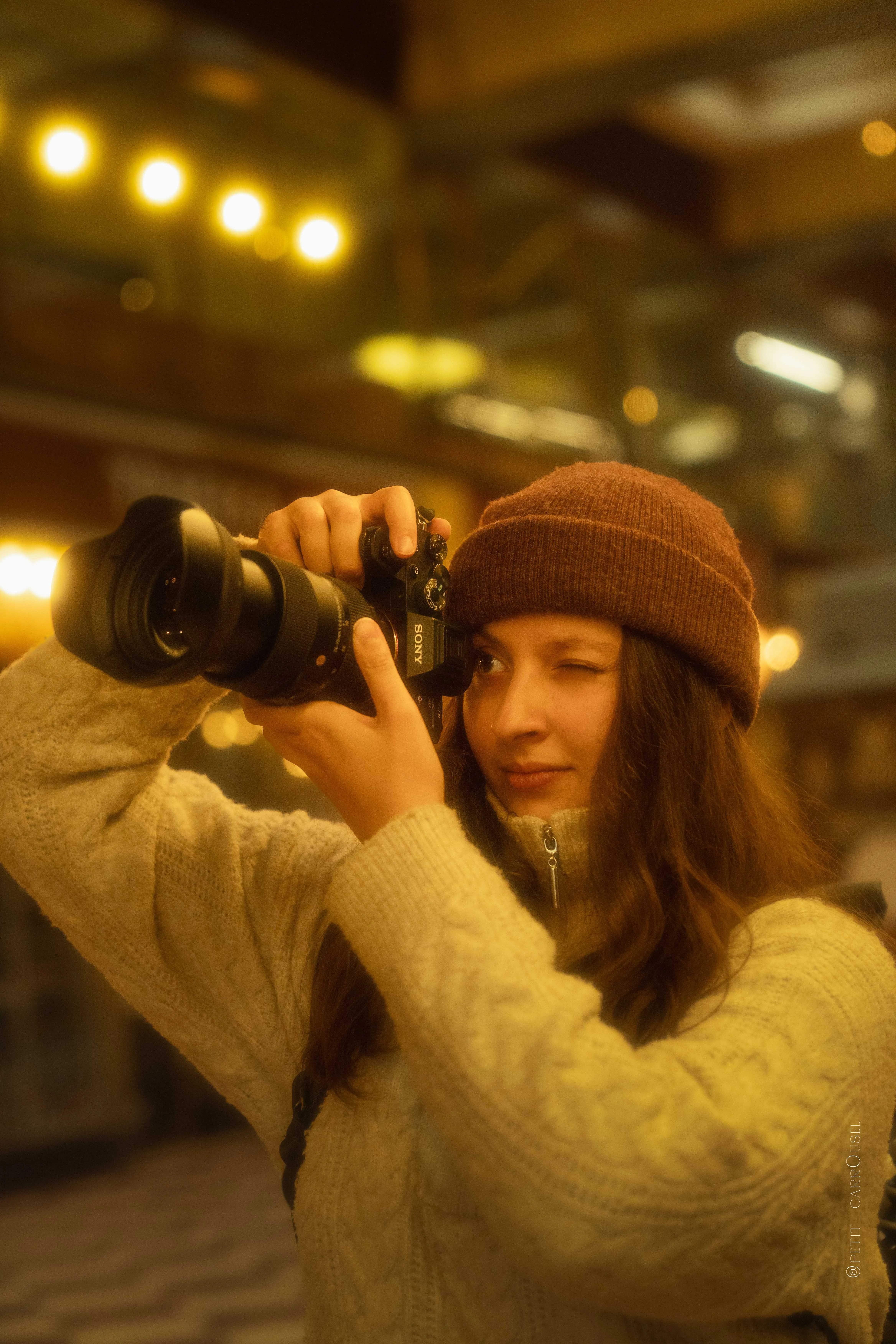 Une photographe cadre à l'objectif sous les lumières chaudes d'un passage couvert, pendant l'édition Prague.