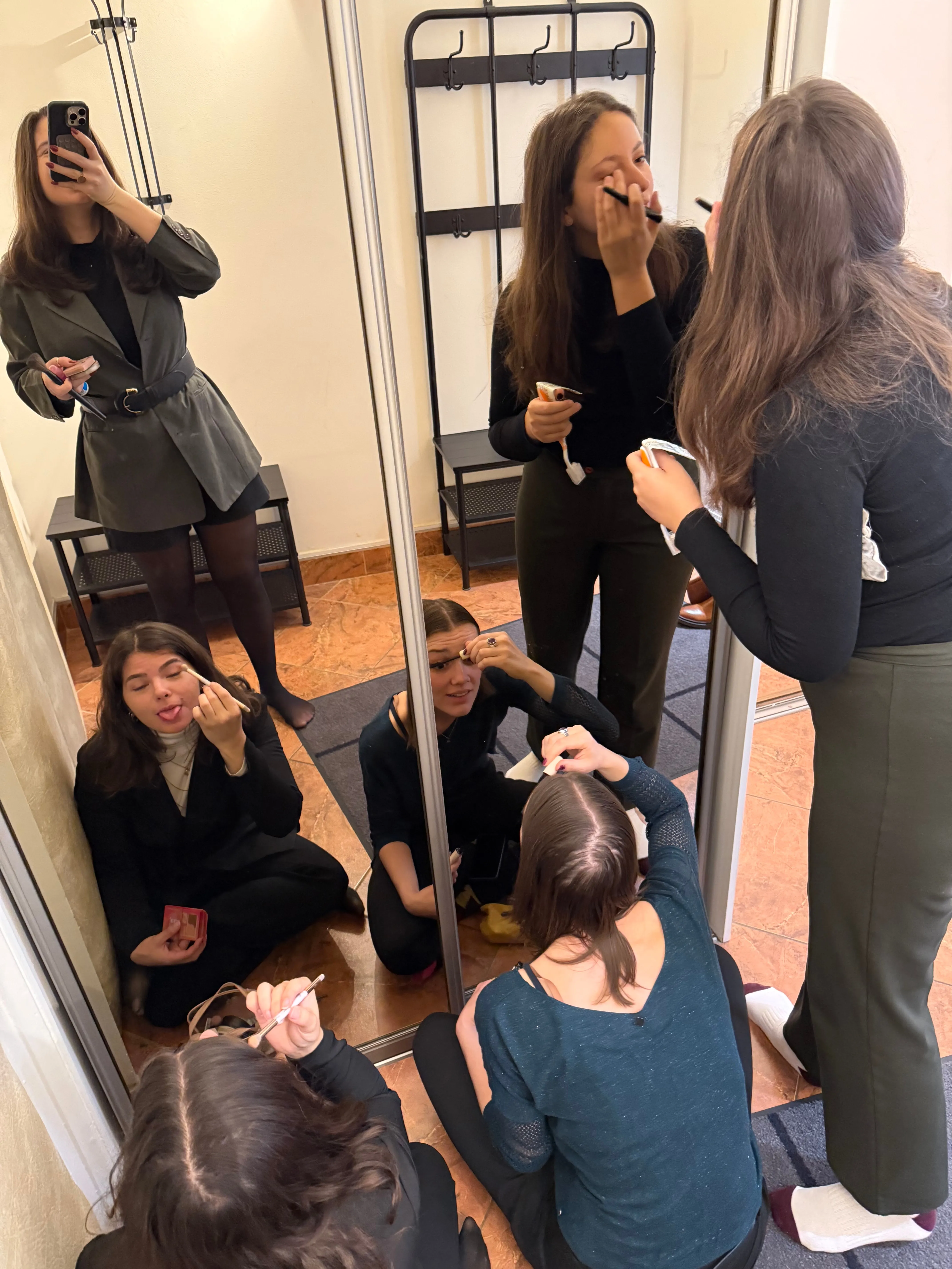 Les participantes se maquillent ensemble devant un grand miroir avant la séance photo à Prague.