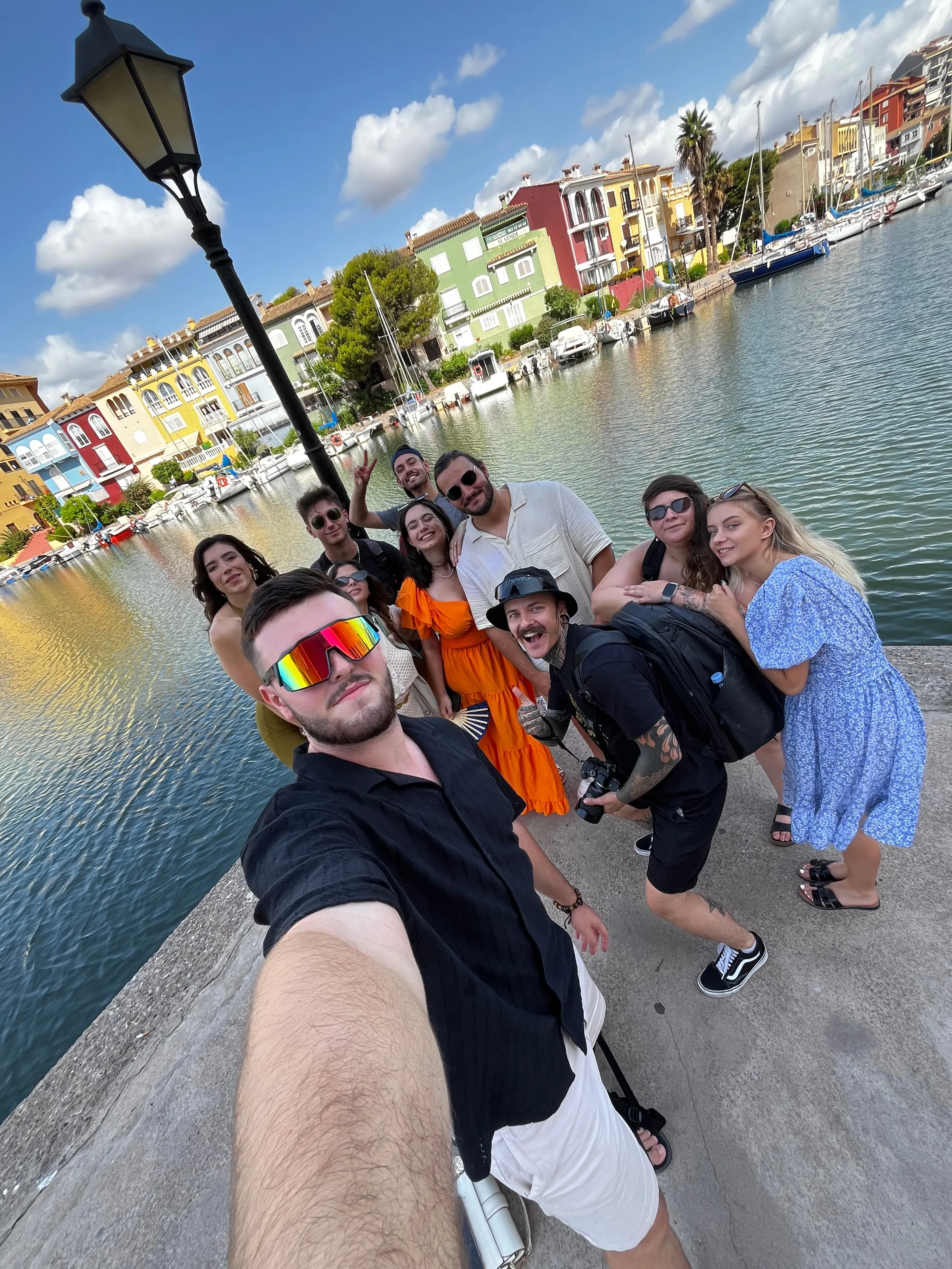Selfie du groupe sur un quai, devant un port bordé de maisons colorées.